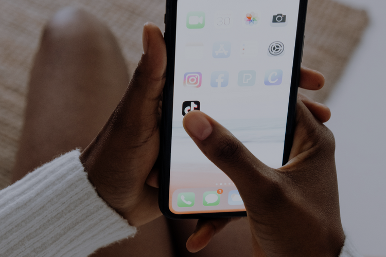 En hand som håller en smartphone och är på väg att trycka på TikTok-appen på skärmen.